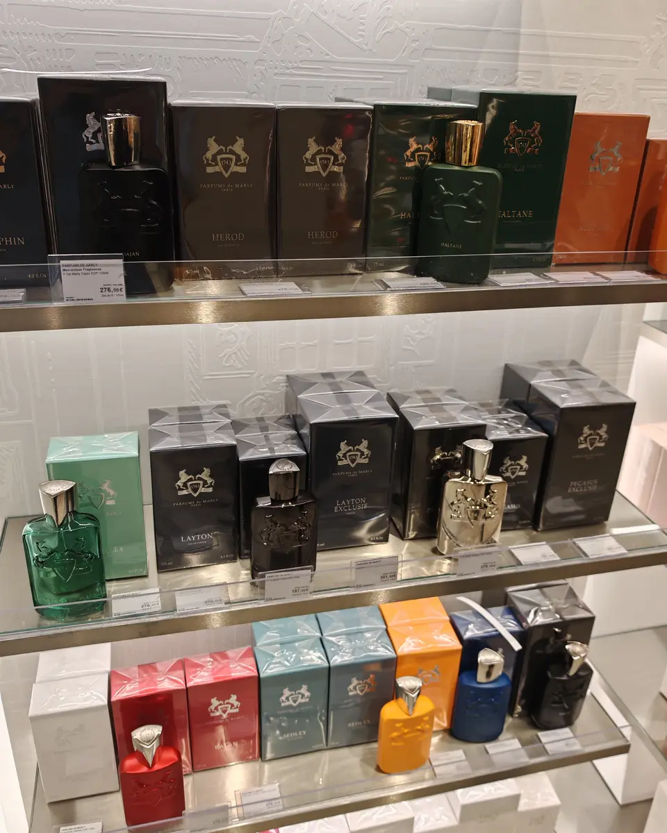 Glass shelves of Parfums de Marly bottles and their black and white boxes in a perfumery